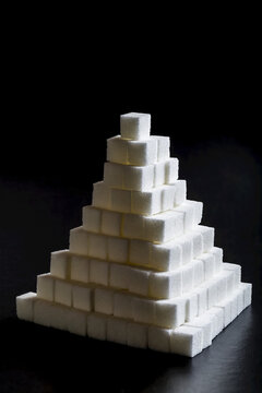 Sugar cubes stacked up as a pyramid on a black background