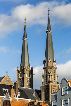 Two tall church spires, one with clock and blue sky and clouds; Delft, South Holland, Netherlands