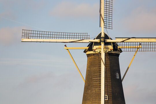 Old wooden windmill with warm sunset light and blue sky; Leiden, Netherlands