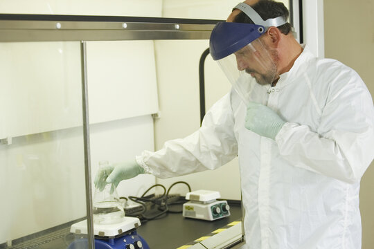 Scientist standing at a fume hood with face shield