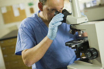 Scientist analyzing a sample through a microscope