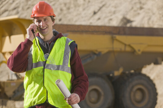 Engineer holding a blueprint and talking on a walkie-talkie