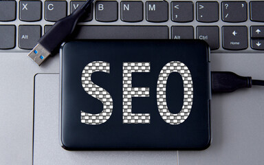 SEO - word on an external drive in gray letters on the background of a laptop