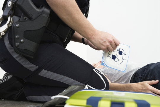 Police woman administering defibrillator to a person