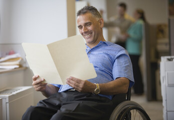 Mid adult man sitting in a wheelchair and reading a document
