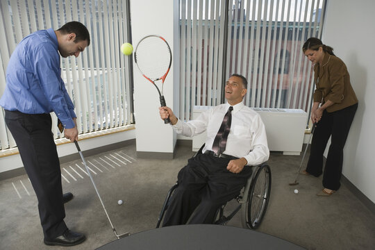 Man and a woman playing golf with a handicapped businessman playing tennis in a wheelchair