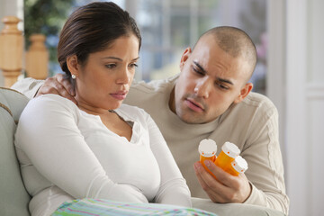 Hispanic man giving medicine to his wife