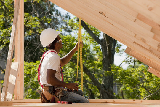 Carpenter measuring roof rafters