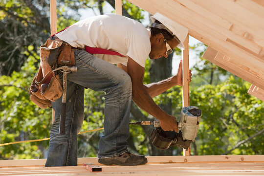 Carpenter working with a nail gun on stud