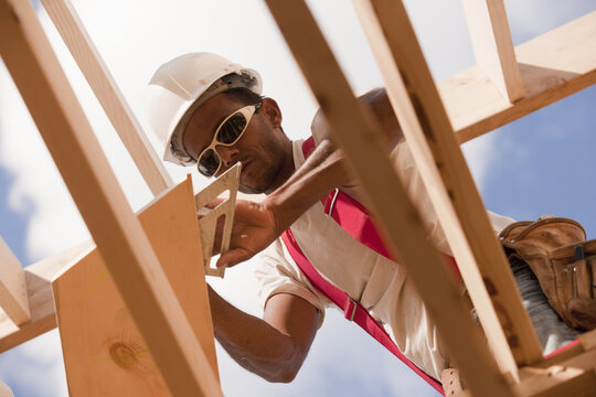 Low angle view of a carpenter marking bevel on a rafter