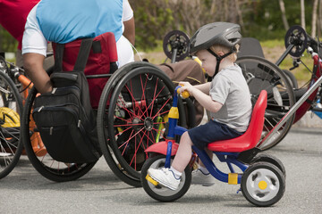 Man with spinal cord injury and boy with joint problems preparing for accessible bike race