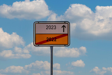 A sign directing from 2022 to 2023 as a concept of a new year over a background of a cloudy sky