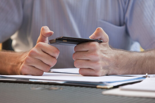 Businessman with Friedreich's Ataxia text messaging on a mobile phone with hand degeneration