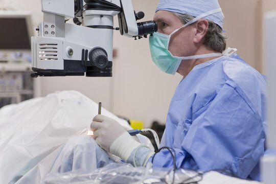 Doctor looking in microscope using a cracker instrument and phaco hand piece during cataract surgery