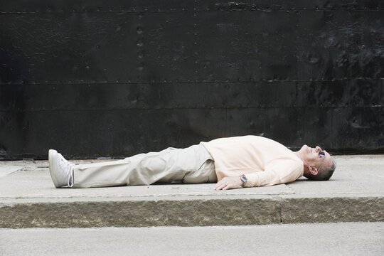 Senior man lying on a road.