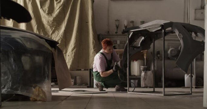 Female painter sanding bumper for priming