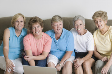 Portrait of a group of middle-aged women sitting together on a couch and smiling