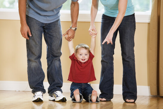 Parents holding hands of their son.