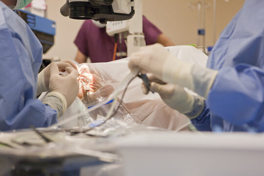 Surgical technologist holding phaco instrument and doctor using a syringe