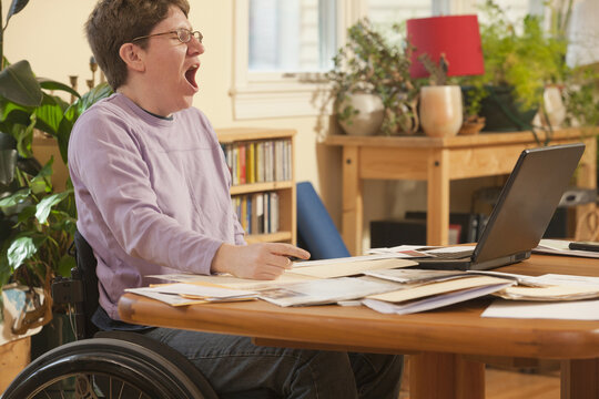 Businesswoman with multiple sclerosis in a wheelchair tired of doing her paperwork
