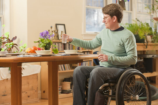 Woman with multiple sclerosis in a wheelchair setting table for dinner