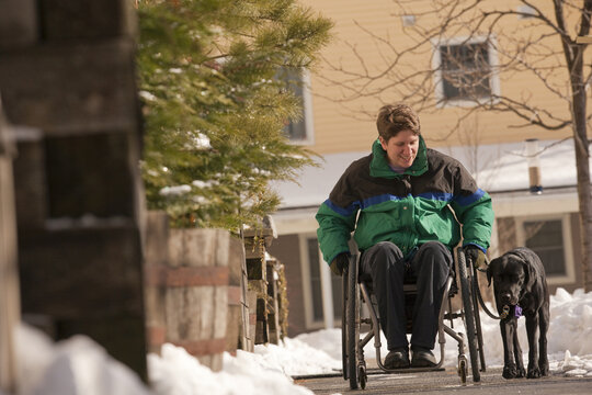 Woman with multiple sclerosis in a wheelchair with a service dog in winter