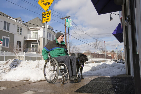 Woman with multiple sclerosis in front of a shop with a service dog
