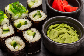 Sushi with cucumber and seaweed. Wasabi in a black bowl.
