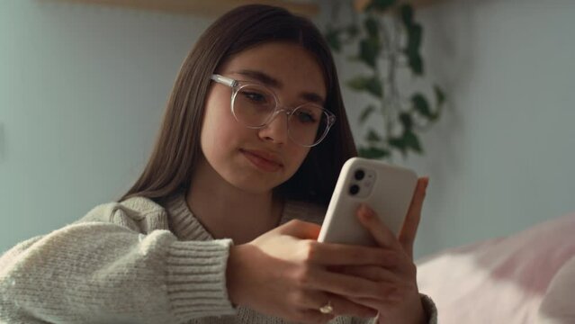Close up of caucasian teenage girl browsing phone in her bedroom. Shot with RED helium camera in 8K.   