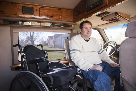 Man with spinal cord injury getting into the driver's seat from his wheelchair in accessible van