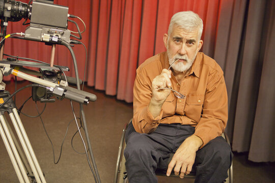Man in wheelchair with muscular dystrophy beside a TV camera in studio