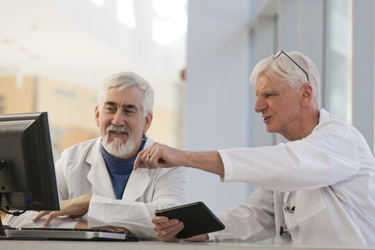 Two doctors discussing information on a computer and a tablet, one with Muscular Dystrophy