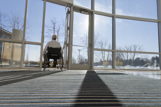 Doctor with muscular dystrophy in wheelchair leaving hospital entrance