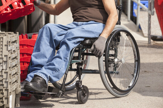 Loading dock worker with spinal cord injury in a wheelchair stacking inventory trays