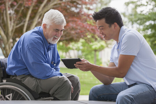 Engineer with muscular dystrophy and diabetes in his wheelchair talking with design engineer using tablet