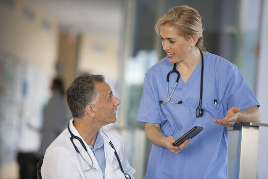 Doctor in wheelchair with spinal cord injury talking with nurse about information on tablet
