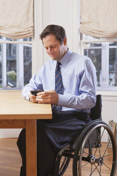 Businessman with spinal cord injury in a wheelchair using a smartphone