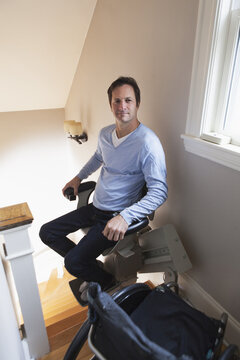 Man with spinal cord injury at top of stairs in his motorized stair lift