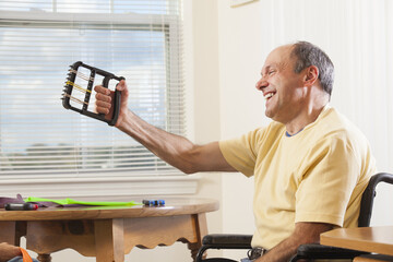 Man with Friedreich's Ataxia in a wheelchair using hand strengthening equipment