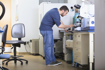 Engineering student turning on chemical analysis equipment in a laboratory