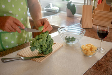 Male hands cutting healthy broccoli cabbage on wooden cutting board. Healthy eating concept