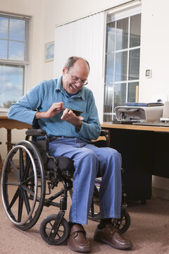 Man with Friedreich's Ataxia in wheelchair using a smartphone with deformed hands