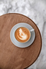 A cup of cappuccino with rose on top on wooden table. Table on the snow.