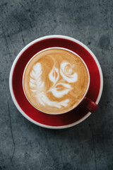 A cup of cuppuccino with rose on top on the table