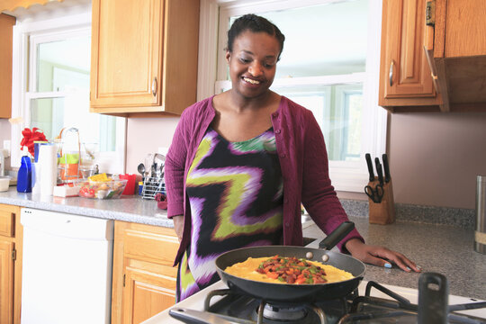 Woman With Learning Disability Cooking In The Kitchen