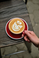 Girl holds red cup of cappuccino
