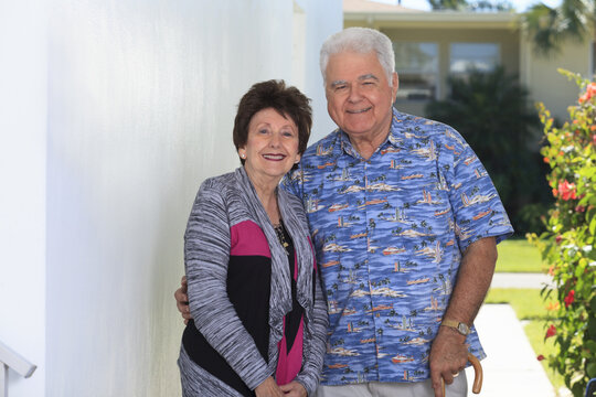 Senior woman standing with her husband with polio holding cane