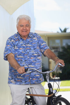 Senior man with polio on bicycle with cane attached