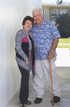 Senior woman standing with her husband with polio holding cane