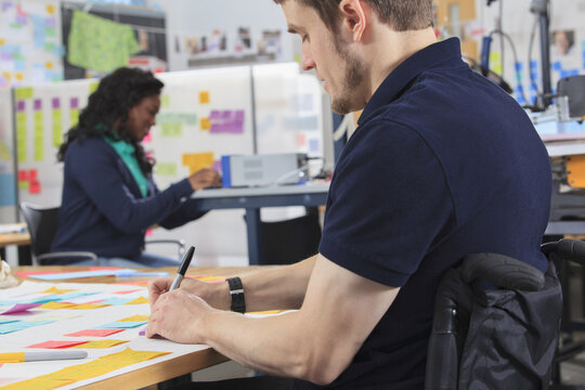 Student preparing ideation notes in an engineering fabrication laboratory, the man with spinal cord injury
